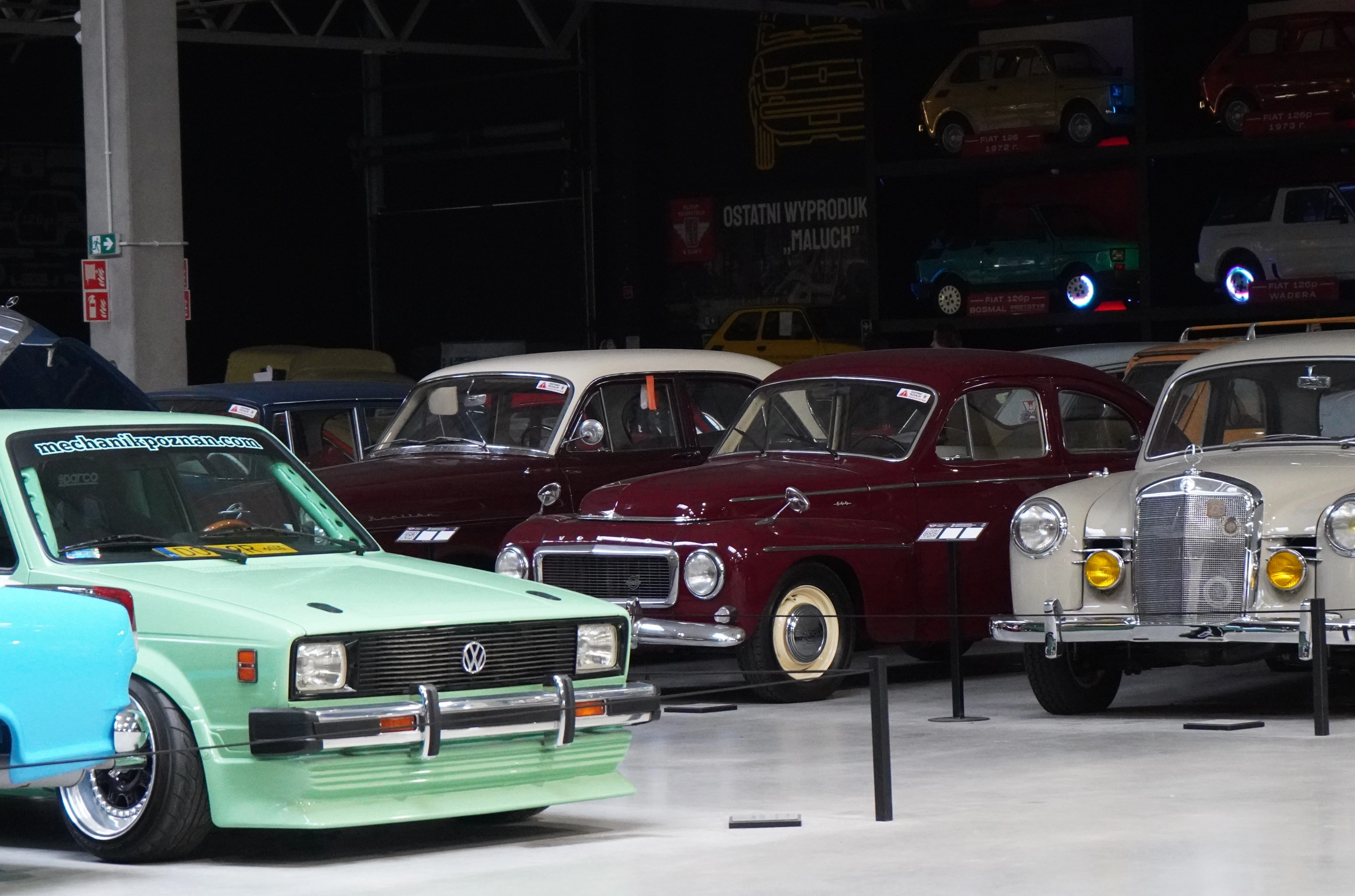 Kolekcja samochodów w Muzeum Wena, zielony Volkswagen z lat 50., w tle warszawskie Syrenki
